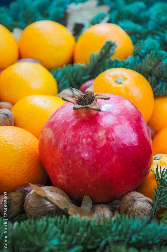 Granatapfel, Mandarinen und Nüsse schmücken in ihrer natürlichen Schönheit den weihnachtlich dekorierten Tisch