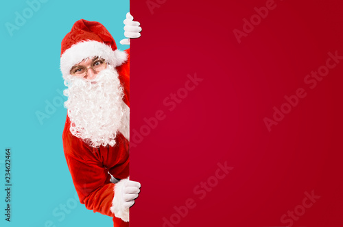 Santa Claus is looking out of colorful advertisement board and copy space © Sergey Peterman
