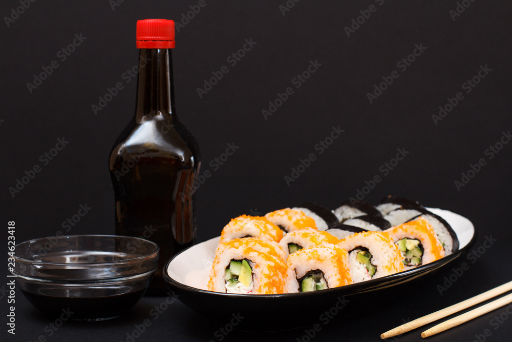 Uramaki California. Sushi rolls, bottle and bowl with soy sauce.