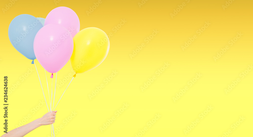hand hold coloured balloons isolated on yellow background, holiday and fun hand hold coloured balloons isolated on yellow background, holiday and fun