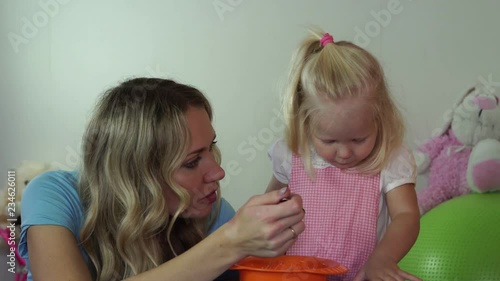 child refuses to eat porridge. Mom is trying to feed her daughter porridge.