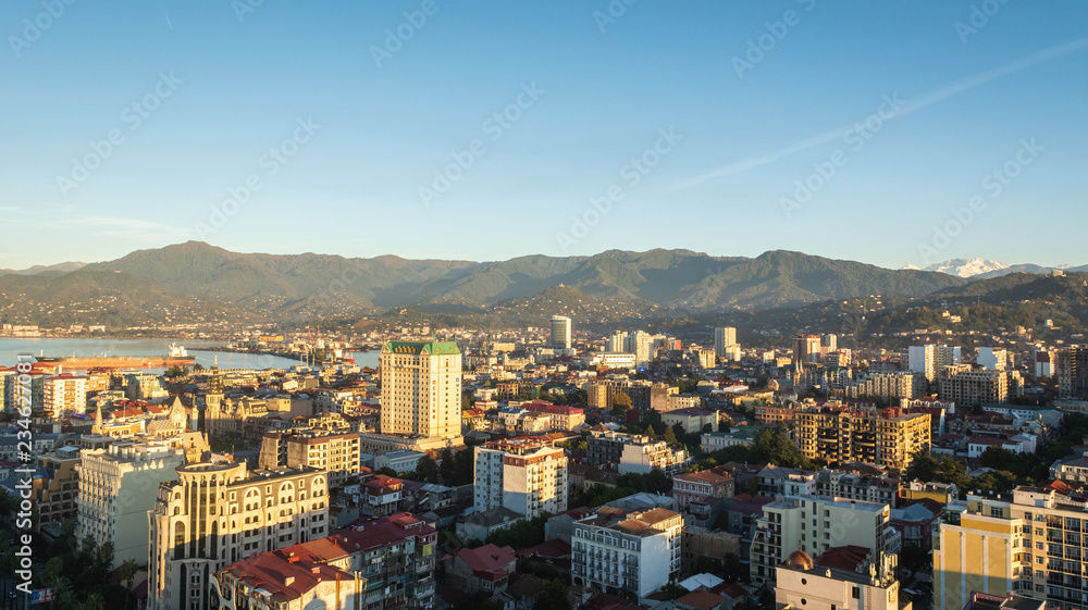 Batumi, Adjara, Georgia - October 2018: cityscape seen from the top of Sheraton sky bar during sunset golden hour with mountains in background