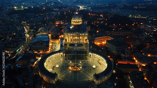Aerial drone night view of Saint Peter's square in front of world's largest church - Papal Basilica of St. Peter's, Vatican -an elliptical esplanade created in the mid seventeenth century, Rome, Italy