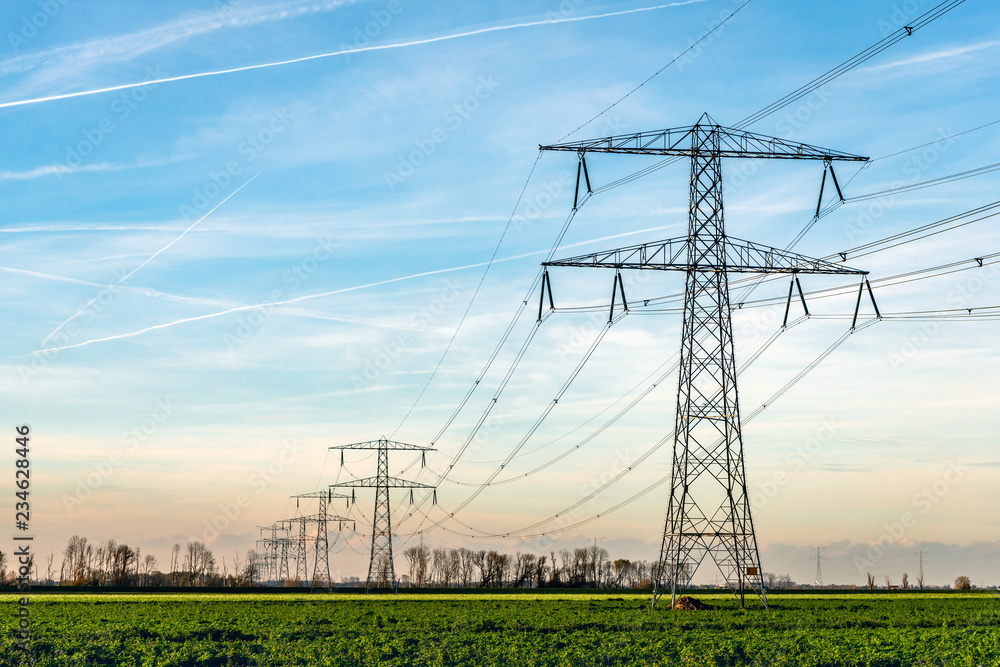 High voltage towers with thick hanging power cables in a rural landscape in the Netherlands