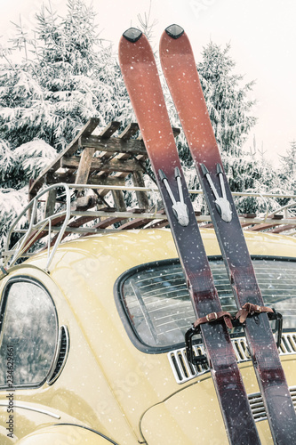 Classic car with vintage ski's and sled during snowfall