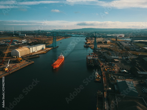Teesside transporter bridge with bulk carrier ship sailing under it showing industrial river