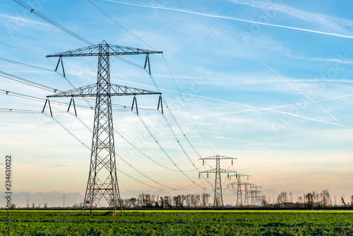 Photography Overview of power pylons and high voltage lines in a long row in a rural landscape
