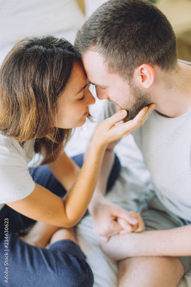 Portrait of happy and beautiful couple on the bed with white linen