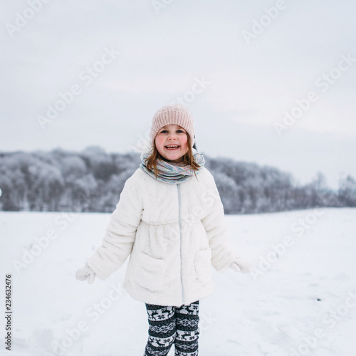 portrait of a baby girl sitting on a sled in a winter park outdoors