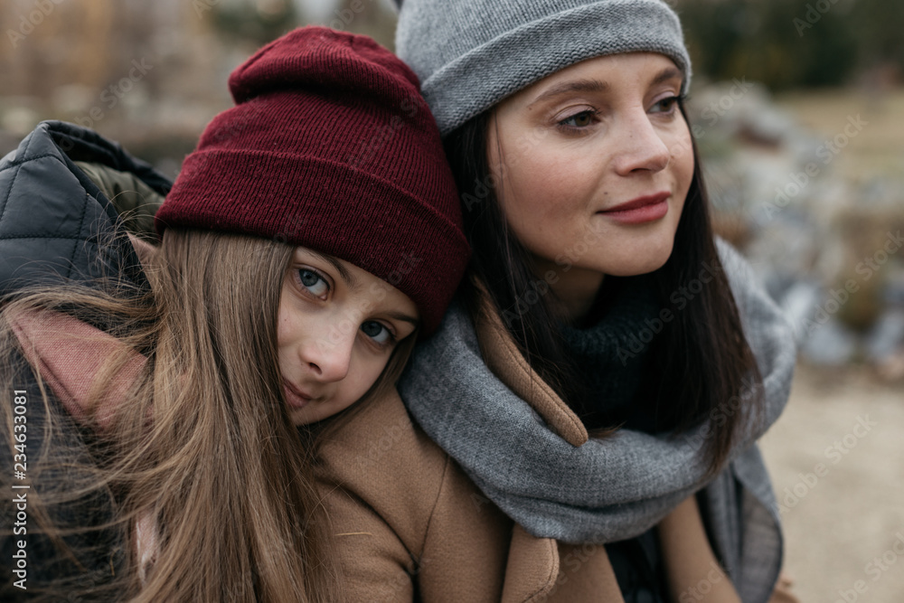 Mother and doughter teenager are walking on the street in warm autumn clothes Mother and doughter teenager are walking on the street in warm autumn clothes
