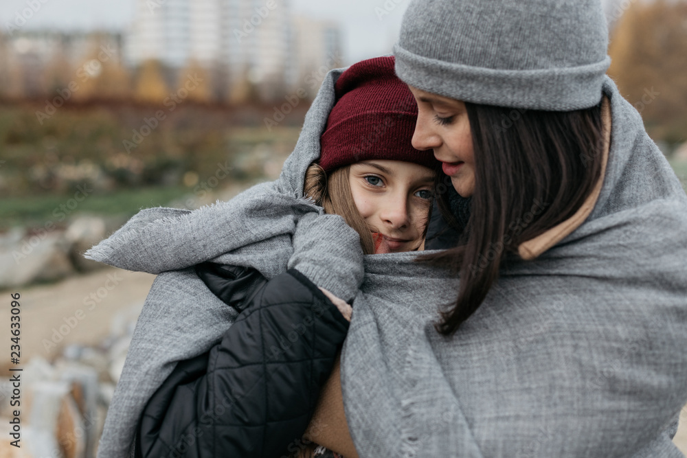 Mother and doughter teenager are walking on the street in warm autumn clothes Mother and doughter teenager are walking on the street in warm autumn clothes