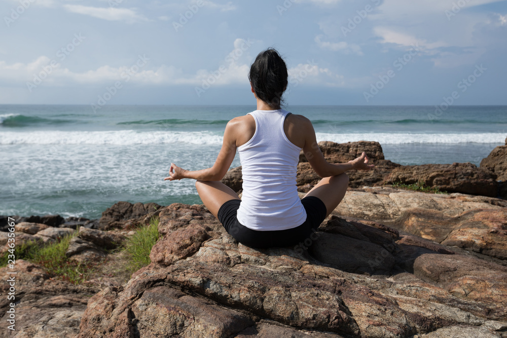 Yoga woman clothing in white meditation at the seaside cliff edge