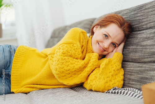 Friendly young woman resting on a sofa photo