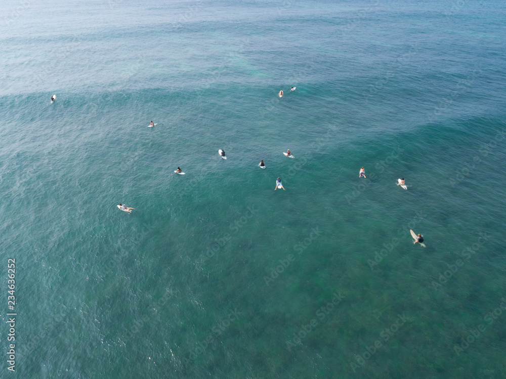 Top view from drone of surfers paddling for catching  waves during surfing  in the indian ocean