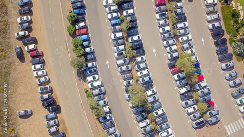 Top down drone image of a public car park with cars, surrounded by green grass.