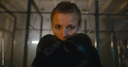 Portrait of female boxer looking into camera at a boxing studio. 4K UHD photo