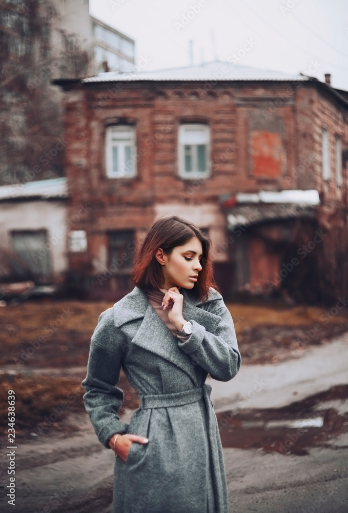 Fototapeta premium Girl in an overcoat outside among old houses