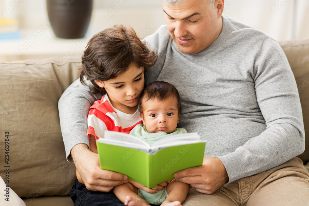 family, fatherhood and people concept - happy father with preteen and baby son reading book at home family, fatherhood and people concept - happy father with preteen and baby son reading book at home