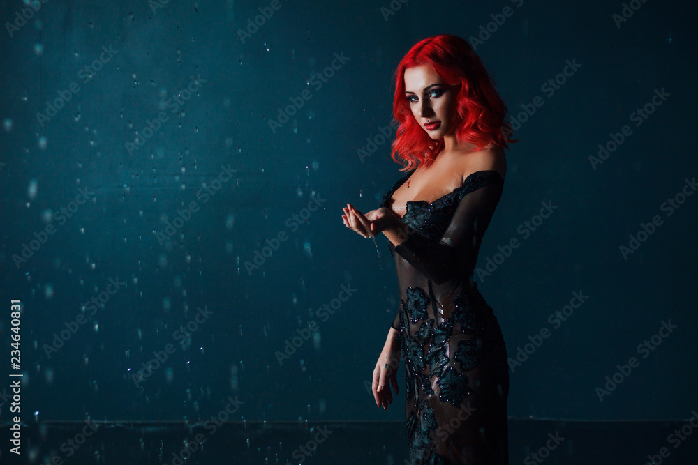 Gothic girl with red hair looking at the camera.  Model in a black dress