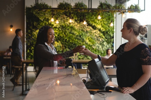 Waitress serving coffee to customer at cafe photo