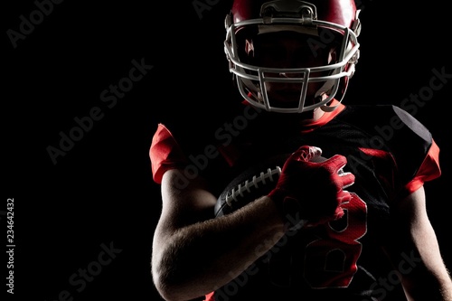 American football player in helmet holding rugby ball