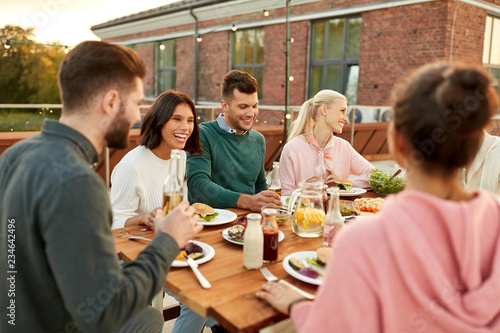 leisure and people concept - happy friends having dinner or rooftop party in summer