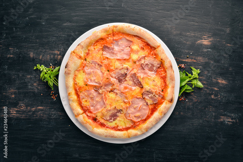 Pizza with ham and Parmesan cheese. On a wooden background. Top view. Free space for your text.