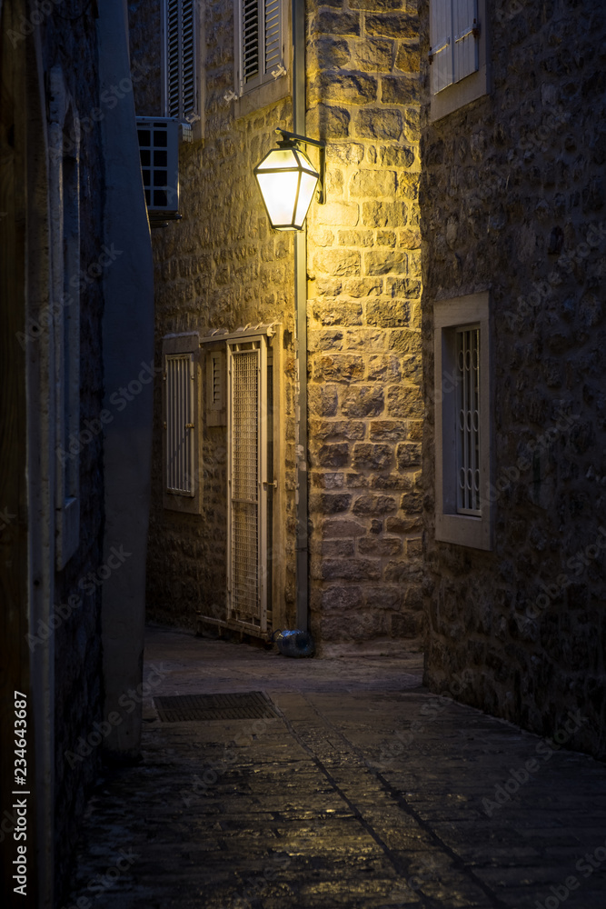 Fototapeta premium Stara ulica w nocy oświetlona zabytkowymi latarniami.