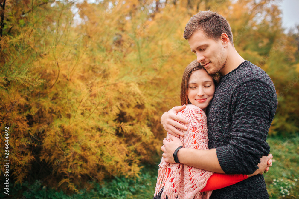 Lovely picture of couple embracing. They keep eyes closed and enjoying the moment. People stand in autumn park. Lovely picture of couple embracing. They keep eyes closed and enjoying the moment. People stand in autumn park.