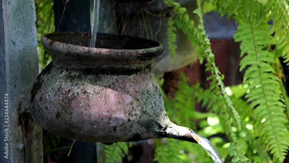 Water cascade from pots on pillar with flowing water in a tropical garden, Thailand. Garden water fountain featuring Water cascade from pots on pillar with flowing water in a tropical garden, Thailand. Garden water fountain featuring