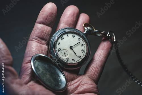 old man holds in his hand a retro pocket watch on a chain, the concept of a bygone time and old age