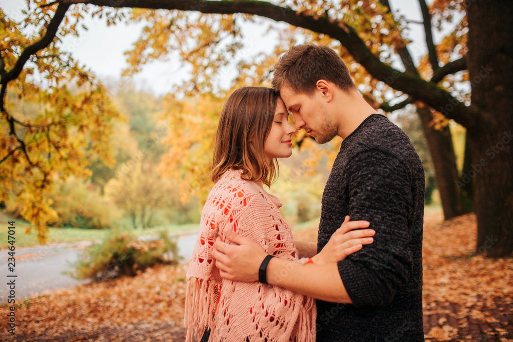 Fototapeta premium Calm and peaceful picture of couple leaning to one another. They keep their foreheads together. Couple is in park.