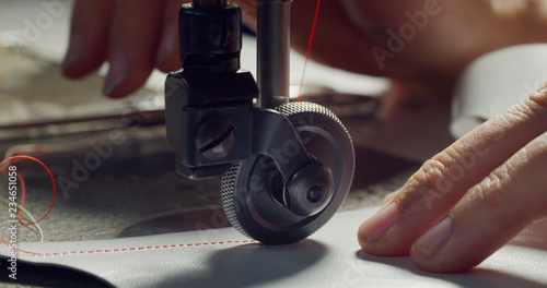 Foto Close up of a shoemaker sewing a red leather by using a sewing machine according to the italian tradition