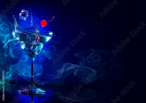ice and cherry falling in a cocktail splash on blue smoky background