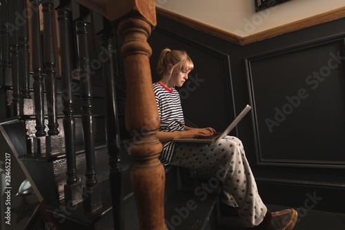 Woman using laptop on stairs at home photo