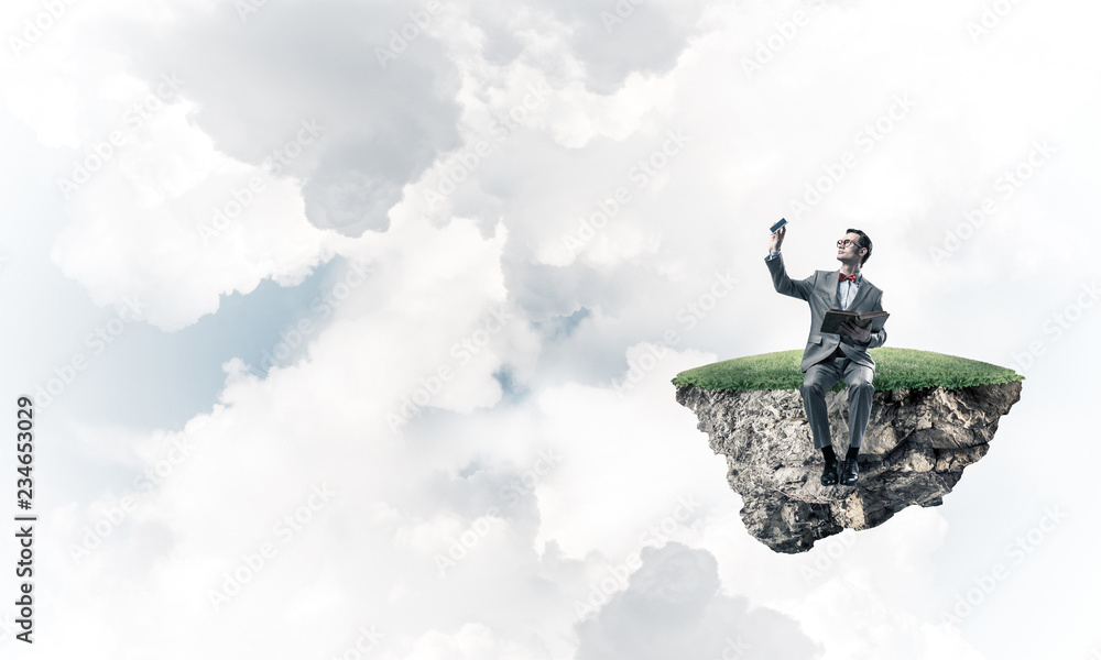Young businessman or student floating in sky and studying the sc Young businessman or student floating in sky and studying the sc