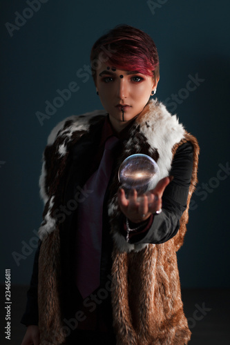 Girl shaman on dark background stuck out his hand, hand over the magic ball