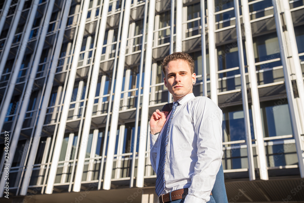 Businessman in classy suit holding his jacket on background of modern office skyscraper. Businessman in classy suit holding his jacket on background of modern office skyscraper.