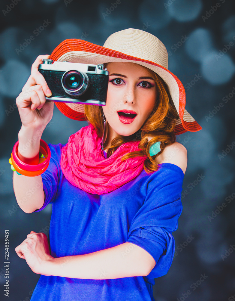 Stylish redhead girl in hat with camera and bokeh on background Stylish redhead girl in hat with camera and bokeh on background