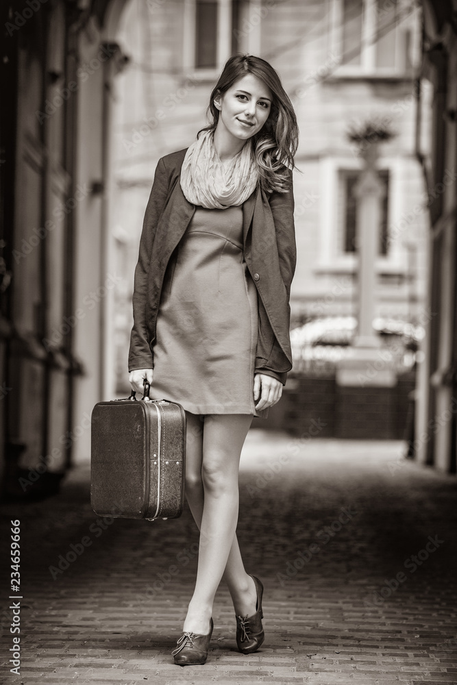 portrait of a beautiful girl with suitcase on the street. Image in black and white color style