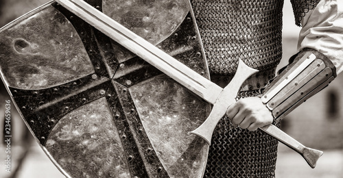 Closeup view on traditional medieval knight with shield and sword. Image in black and white color style