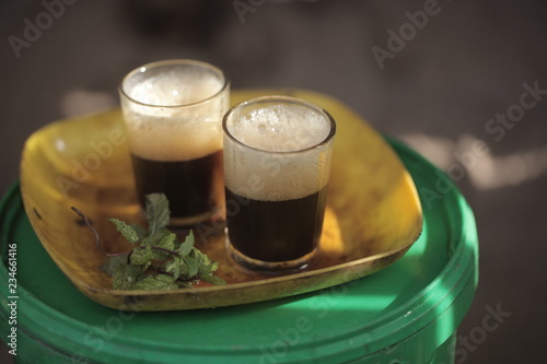 close up of traditional african tea - black strong green attaya in small glasses on a yellow plate, outdoors in the Gambia, Africa