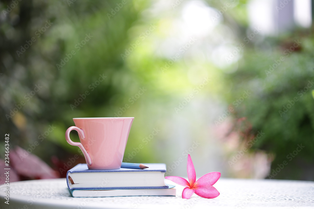 Pastel pink cup with flower and books at outdoor Pastel pink cup with flower and books at outdoor