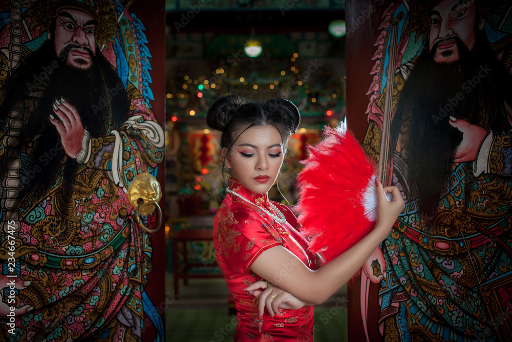 Asian young female model fashion red Chinese dress in the China shrine. Asian girl in red Chinese dress happy Chinese new year in the China temple Thailand 