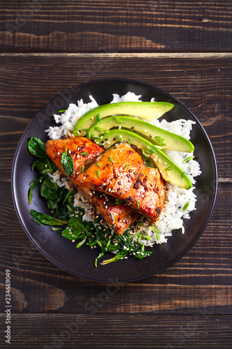 Salmon teriyaki rice bowl with spinach and avocado. View from above, top studio shot