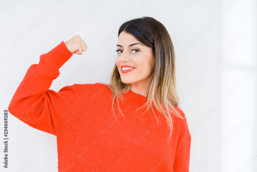Young woman wearing casual red sweater over isolated background Strong person showing arm muscle, confident and proud of power Young woman wearing casual red sweater over isolated background Strong person showing arm muscle, confident and proud of power