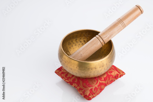 Tibetan Singing Bowl on Red Cushion Isolated on White Background