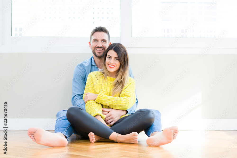 Beautiful young couple in love, kissing and hugging each other sitting on the floor at home Beautiful young couple in love, kissing and hugging each other sitting on the floor at home