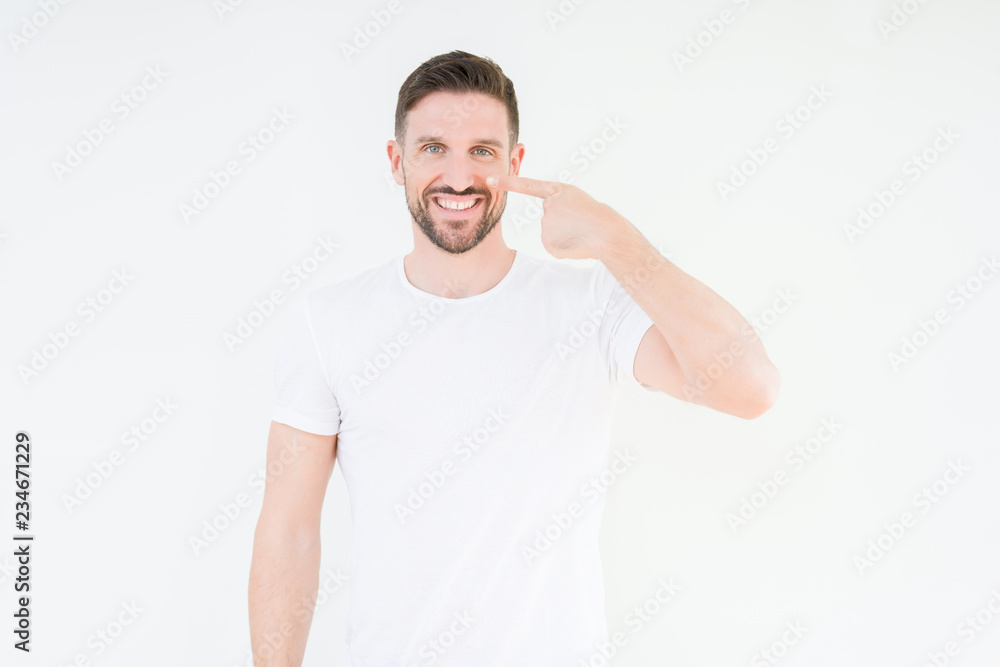 Young handsome man wearing casual white t-shirt over isolated background Pointing with hand finger to face and nose, smiling cheerful Young handsome man wearing casual white t-shirt over isolated background Pointing with hand finger to face and nose, smiling cheerful