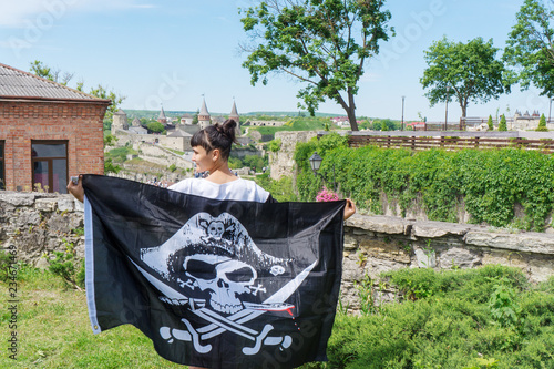 A girl looks at a castle with a pirate flag.